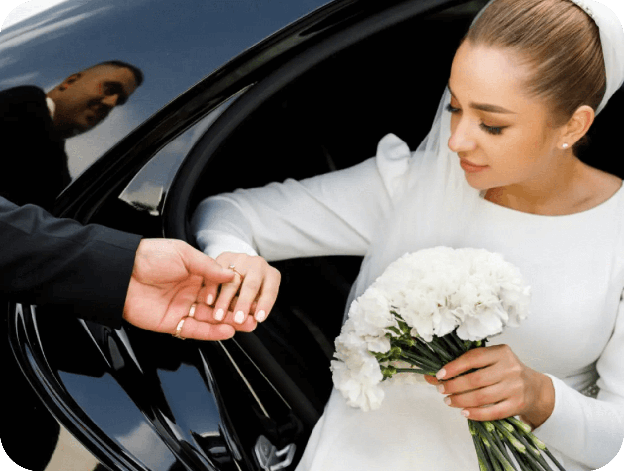 Bride exiting car, holding bouquet, receiving help.