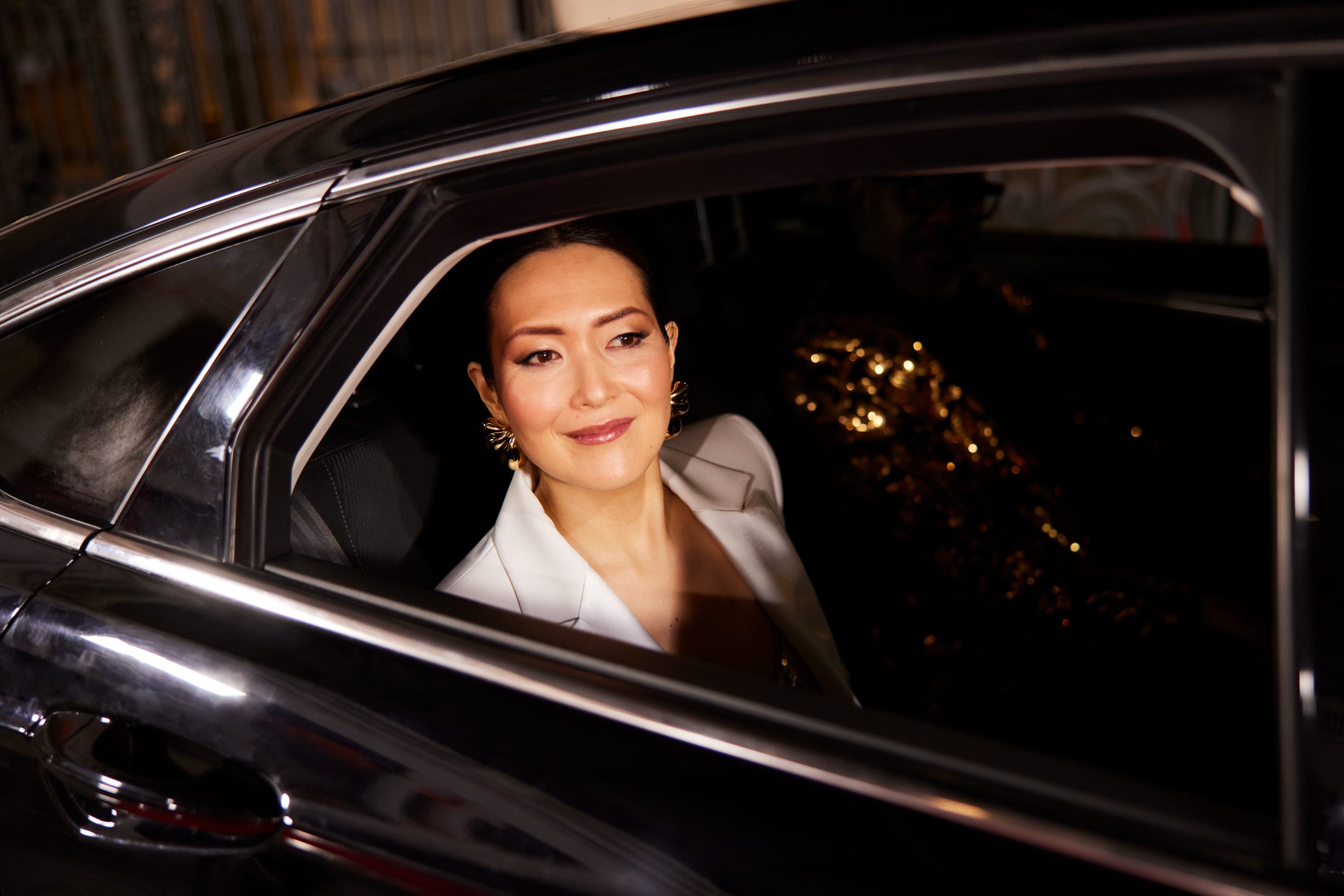 A woman smiling inside a car at night.