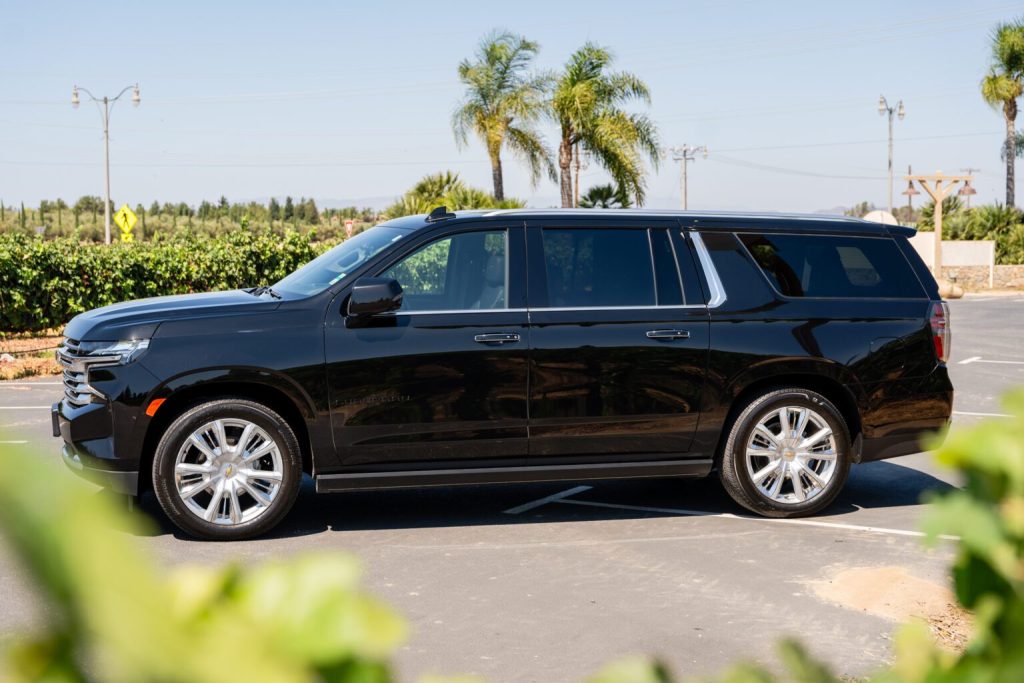 Black luxury SUV parked outdoors with palm trees in the background.