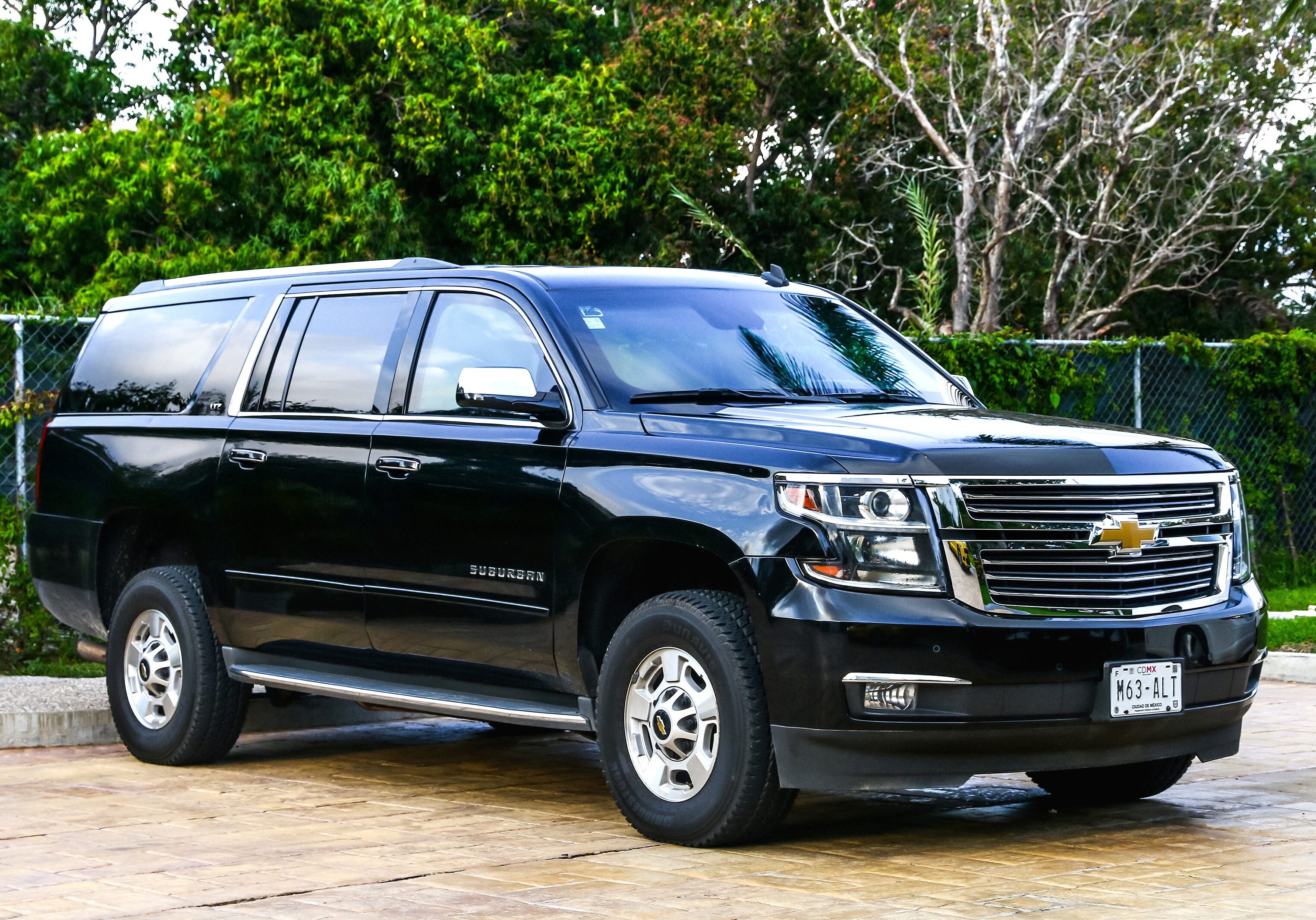 Black Chevrolet Tahoe SUV parked outdoors near trees.